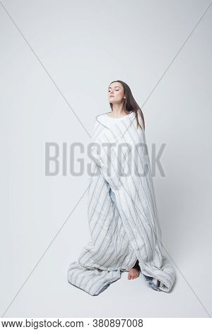 Healthy Sleep And Drowsiness, Beautiful Young Woman Standing Wrapped In A Blanket, Light Gray Backgr
