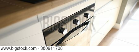 Close-up Of Modern Luxury Black Cookstove Embedded In Kitchen Table. Rays Of Sun On Kitchenware. Ren