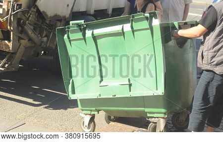 Dustman Worker Is Moving Empty Garbage Container From Truck.
