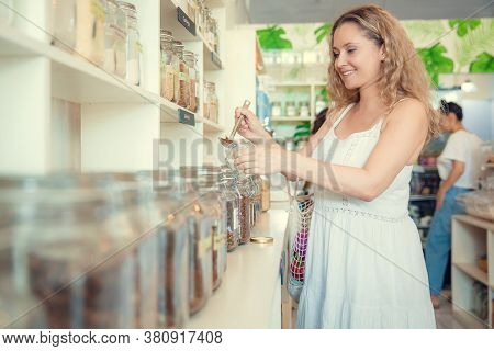Young Woman Filling Up Oragnic Food In Zero Waste Plastic Free Store. Low Waste Lifestyle. Sustainab