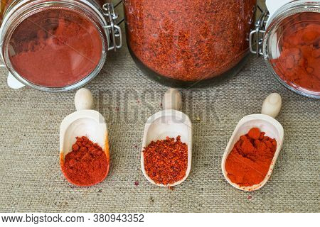 Smoked Hot Paprika, Sweet Paprika And Chopped Paprika In Wooden Scoops And Jars On Background