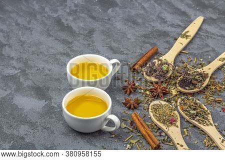 Assortment Of Different Grade Dry Tealeaf In Wooden Spoons And Two Cup Of Green Tea. Organic Herbal,