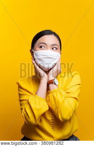 Asian Woman Wearing Protective Face Mask Isolated On Yellow Background.
