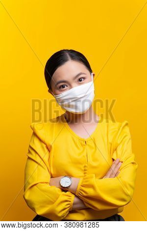 Asian Woman Wearing Protective Face Mask Isolated On Yellow Background.