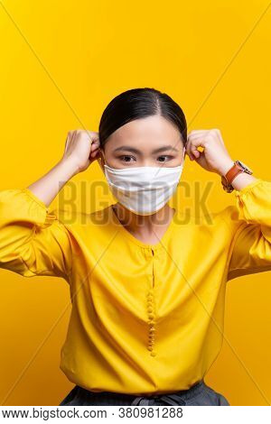 Asian Woman Wearing Protective Face Mask Isolated On Yellow Background.