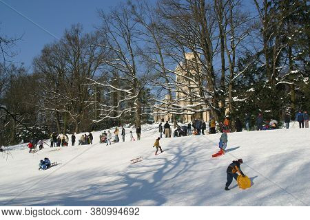 ZAGREB, CROATIA - JANUARY 12, 2014: Landscape view of a snowy hill with families with children and people sledging and having fun in snow, Park Maksimir in Zagreb, Croatia