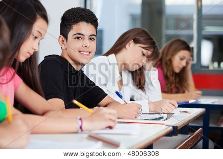 Porträt von Teenager sitzen mit Freunden schreiben am Schalter im Klassenzimmer