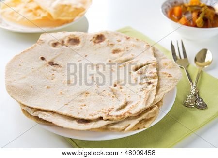 Chapatti roti nebo plochý chléb, papadom a kari dhal. Indické potraviny na jídelní stůl. 