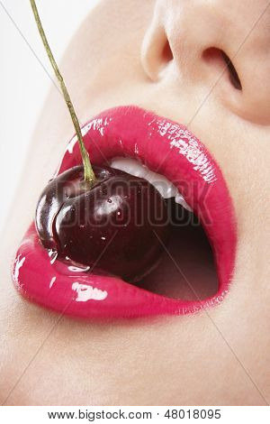 Closeup smyslný mladé ženy nosí růžovou rtěnku kousání cherry