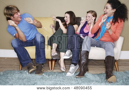 Młode kobiety, rzucanie popcorn kolegę na kanapie