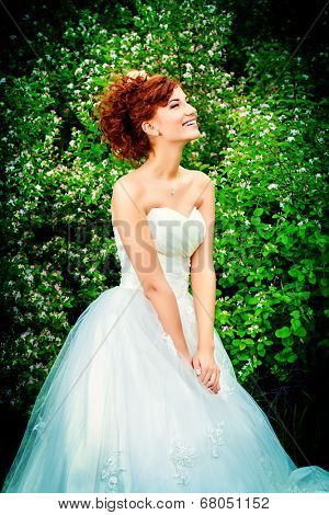 Beautiful smiling bride with chaming red hair. Wedding dress and accessories. Wedding decoration. 