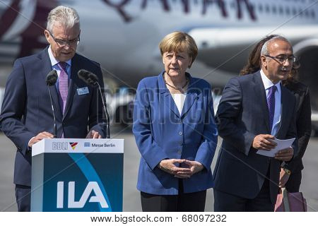 BERLIN, GERMANY - MAY 20, 2014: German Chancellor Angela Merkel (C) and Turkish Minister of transport Lutfi Elvan (R) open up the International aviation and space exhibition ILA.