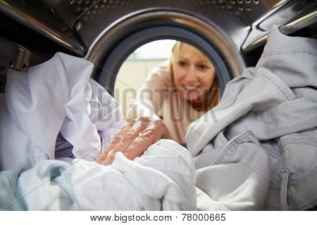 Woman Doing Laundry Reaching Inside Washing Machine