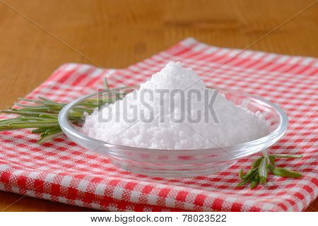 heap of sea salt served in the glass bowl with the fabric linenen and fresh rosemary