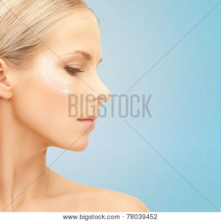 beauty, plastic surgery, aging, people and health concept - beautiful young woman face with lifting arrows over blue background