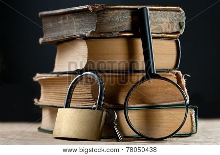 Pile Of Old Books With Keylock And Magnifying Glass