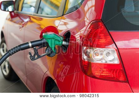 Red car at gas station being filled with fuel