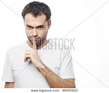 life style  and people concept: young man wearing white t-shirt making silence gesture, shhhhh!!