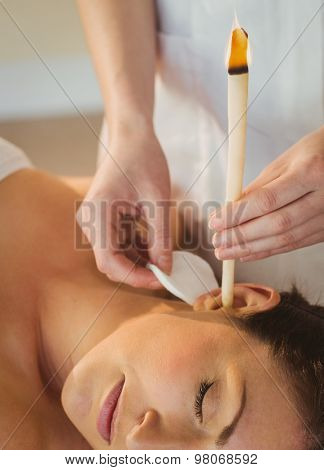 Young woman getting an ear candling treatment in therapy room