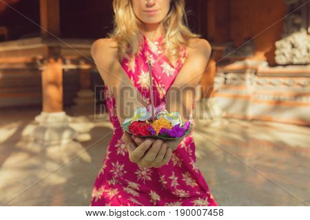 Woman holding canang sari - offering for Gods. Balinese tradition.