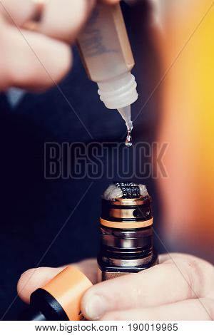 Close-up of a man dripping a fragrant liquid on a cotton wool electronic cigarette. Nichrome heated. The concept of safe replacement of cigarettes and tobacco.
