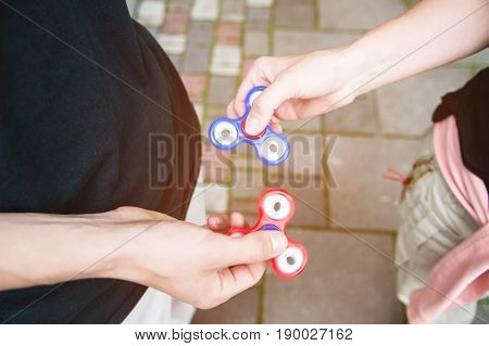 Close-up Two boyfriends tweens spinners on the street against each other Two fidget spinners