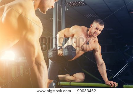 very power athletic guy , execute exercise press with dumbbells, in sport hall