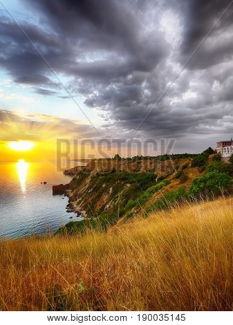 Dramatic sunset at cape Fiolent with bush and grass at foreground. Crimea