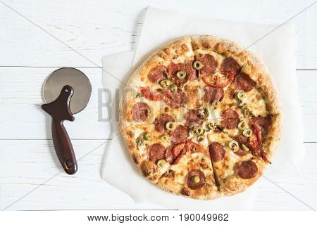 Top View Of Italian Pizza On Baking Paper And Pizza Cutter