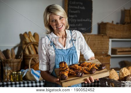 Female staff holding sweet foods in bakery section of supermarket
