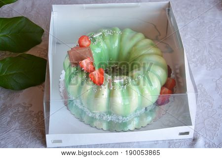 Delicious beautiful luxury homemade mirror glazed mousse cake decorated with chocolate and strawberry packed into cake box on white background