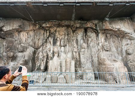 Tourist Take Photo Of Carved Buddha Figure