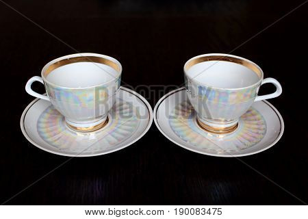 A pair of white iridescent tea cups and saucers
