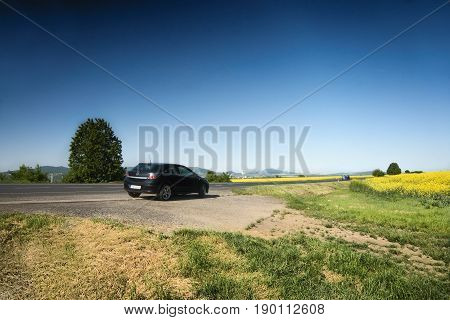 Ceske Stredohori Czech republic - May 19 2017: black car Opel Astra H stand by road between rape fields during spring afternoon
