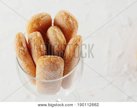 Top view of ladyfinger biscuit cookie in glass jar on white concrete background. Italian cookie savoiardi. Copy space.