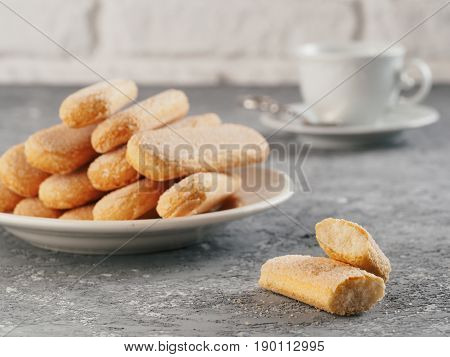 Italian cookie savoiardi and cup of coffee. Close up view of ladyfinger biscuit cookie on gray concrete background. Copy space.