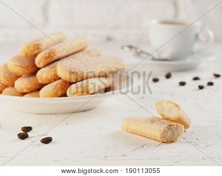 Italian cookie savoiardi and cup of coffee. Close up view of ladyfinger biscuit cookie on white concrete background. Copy space.