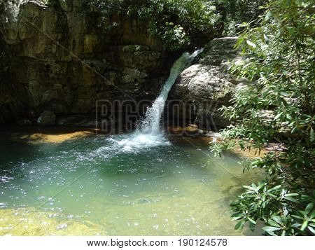 A beautiful waterfall cascading into a large, deep pool at the Blue Hole in East Tennessee, USA.