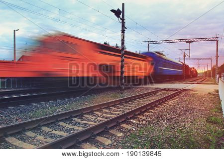 Blurred fast moving train on rails on the railway. The train wagons are moving quickly blurred effect of the departing train into the distance.