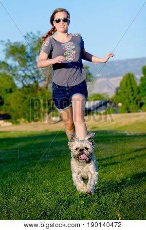 girl running after small dog in the grass