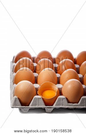Pack of brown chicken eggs in cardboard container isolated on white. One egg is broken.