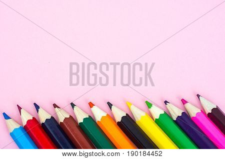 Multicolored pencils on pink paper background. Studio Photo