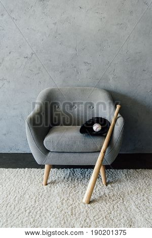Baseball Bat And Ball With Glove On Textile Armchair At Empty Room