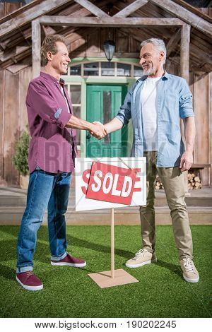 men shaking hands with saleman and buying new house