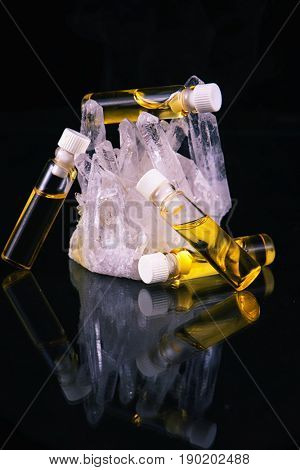 Detail of cannabis oil container and quartz crystal isolated on black - medical marijuana concept