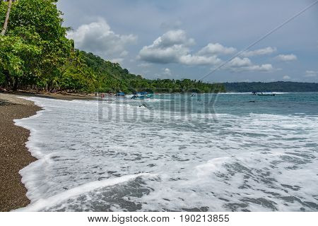 Unrecognizable Tourists enjoy the beach in Corcovado National Park beach and forest, Osa Peninsula, Costa Rica