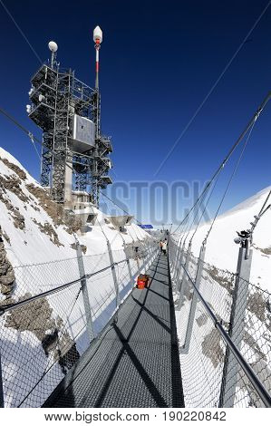 Engelberg, Switzerland - 18 February 2015: People walking on the Cliff Walk in front of transmission antennas of mount Titlis on the Swiss alps