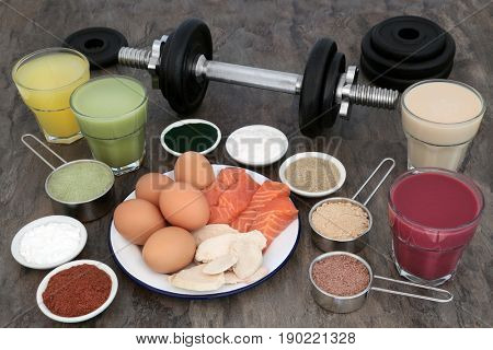 Weight training equipment for body builders with dumbbell weights, high protein meat, fish and dairy with dietary food supplements and drinks.