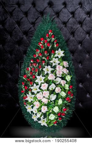 Luxury Funeral wreath with red and white flowers isolated on royal dark background. Ritual object for funeral