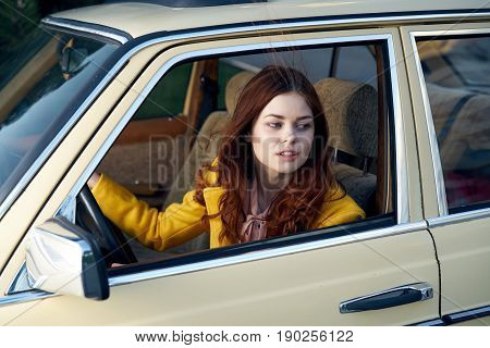 Beautiful young woman in the car, a woman is riding in a retro car.